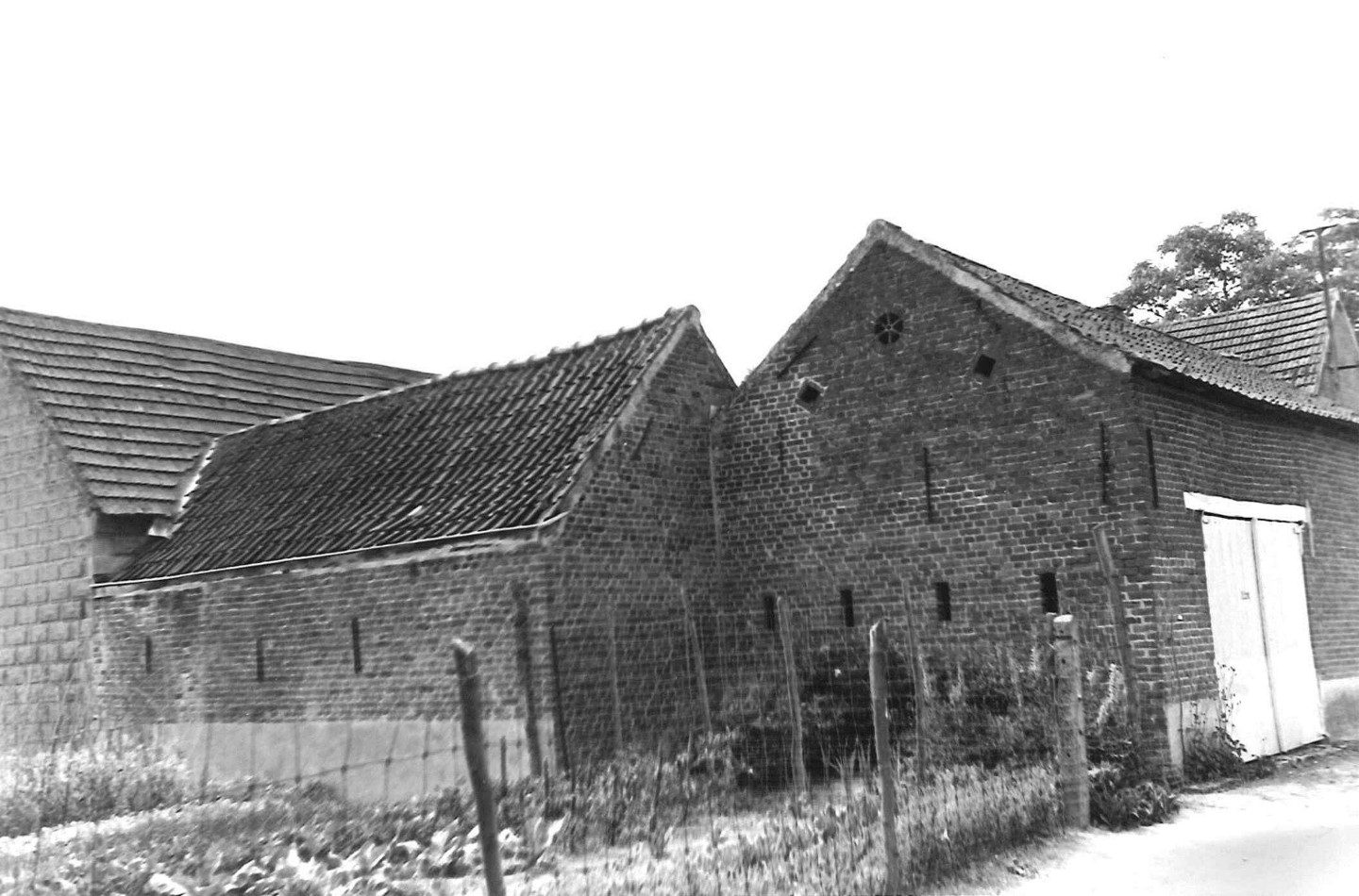 Oude bakstenen hoevegebouwen met pannendaken in de Paellepelstraat in Ninove